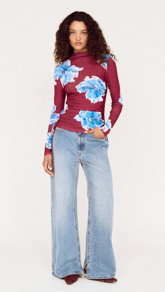 Model wearing a blue floral mesh long sleeve top paired with wide-leg jeans, showcasing a stylish and casual outfit.