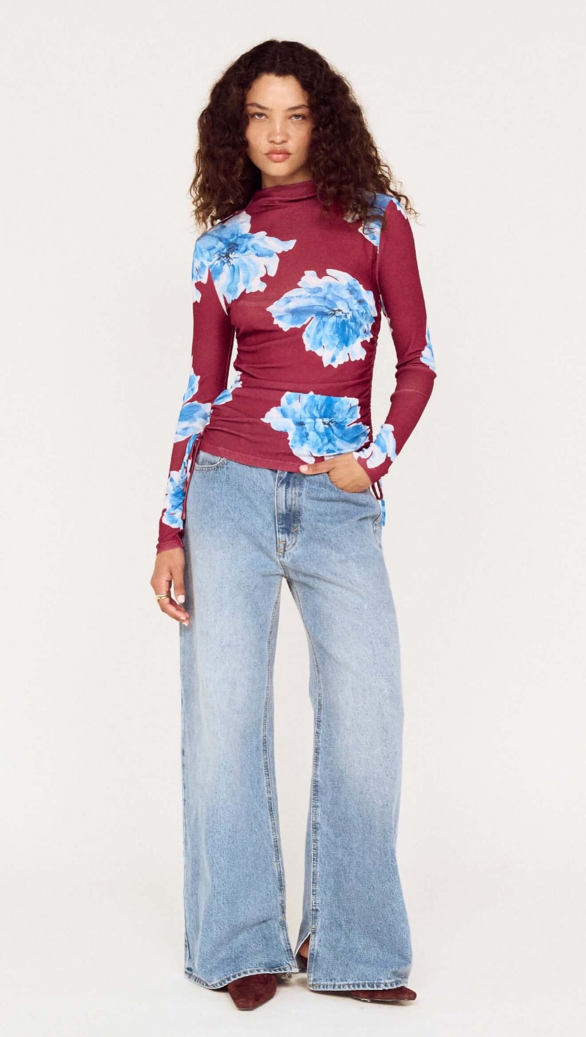 Model wearing a blue floral mesh long sleeve top paired with wide-leg jeans, showcasing a stylish and casual outfit.