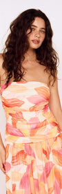 Sunset Leaf Print Sleeveless Midi Dress worn by model, featuring a colorful tropical print and flattering ruched design.