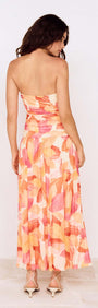 Back view of a model wearing a Sunset Leaf Print Sleeveless Midi Dress with vibrant tropical colors.