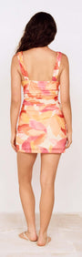Back view of a woman wearing the Sunset Leaf Print Gathered Mini Dress with tropical-inspired print.