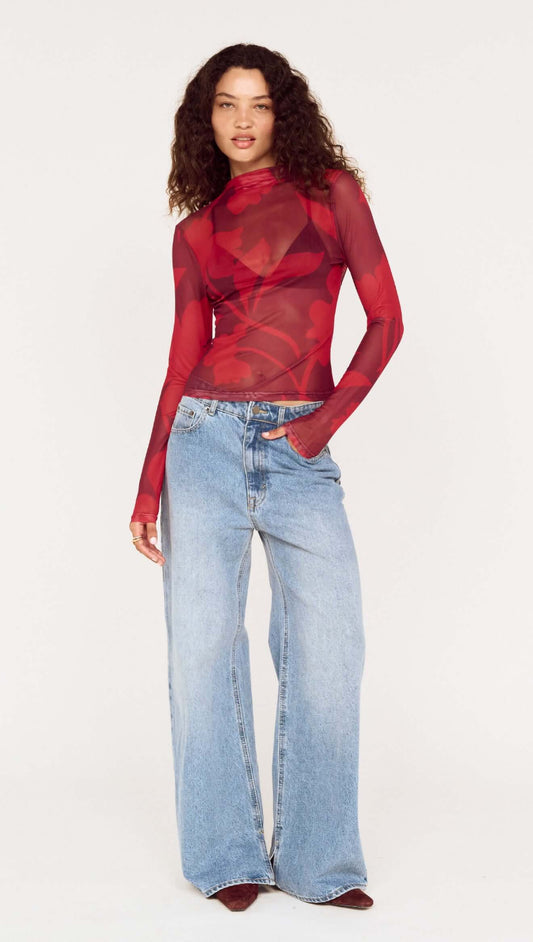 Model wearing an Oversized Floral High Neck Mesh Top with long sleeves, paired with wide-legged jeans, showcasing a stylish look.