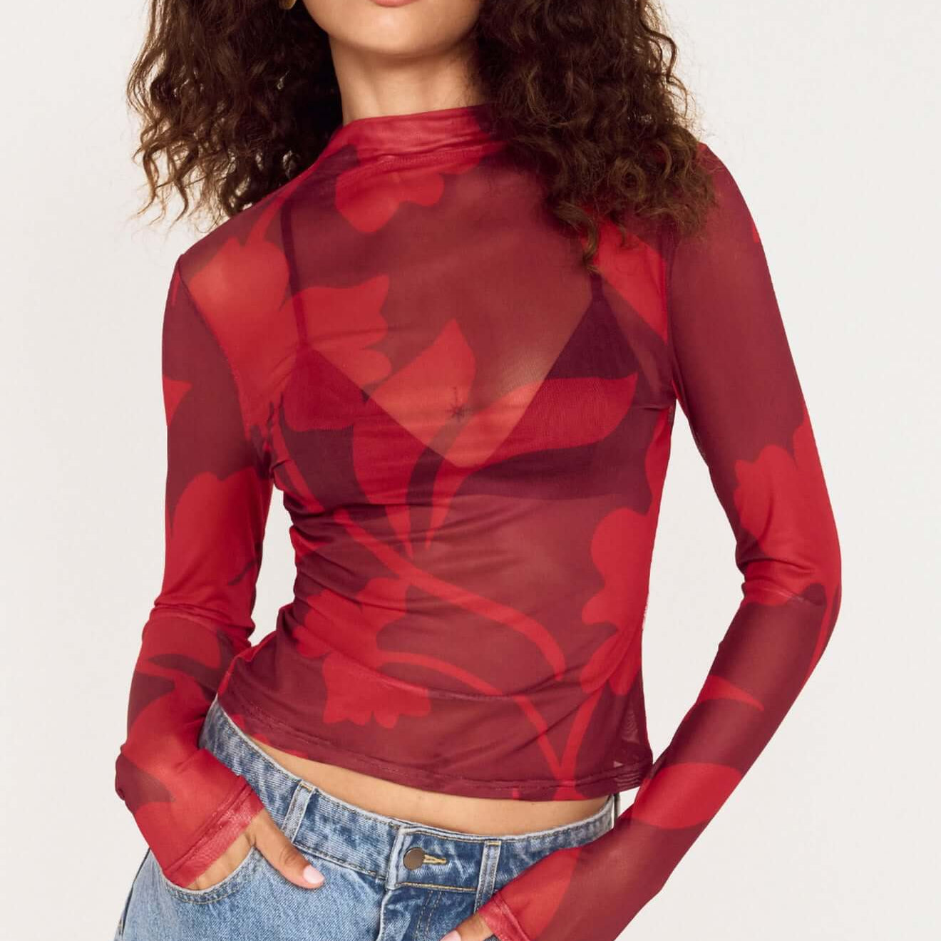 Model wearing an Oversized Floral High Neck Mesh Top in red floral print with long sleeves.