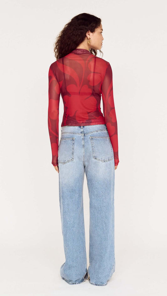 Back view of a model wearing an Oversized Floral High Neck Mesh Top paired with baggy denim jeans.