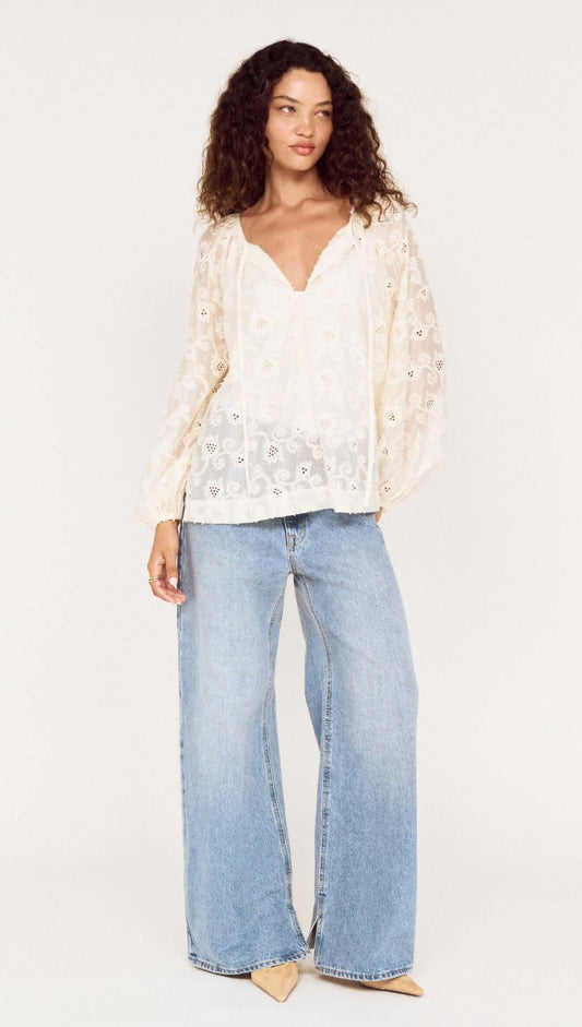 Model wearing a Cream Broderie Baloon Sleeve Blouse with jeans, showcasing its delicate lace and romantic style.