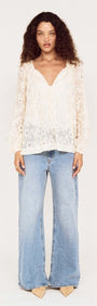Model wearing the Cream Broderie Baloon Sleeve Blouse paired with flared blue jeans, showcasing its delicate design.