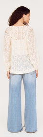 Back view of a model wearing a Cream Broderie Baloon Sleeve Blouse with wide-leg jeans.