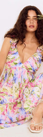 Woman wearing a Watercolour Floral Ruffle Maxi Dress with pastel floral print and ruffle shoulder straps.