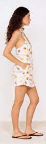 Side view of a woman wearing a Fruit Print Halter Neck Romper with pockets, showcasing a playful fruit-inspired design.