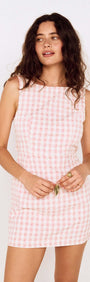 Pink Gingham Tie Back Cotton Mini Dress modeled by a woman with wavy hair, showcasing its fitted silhouette and open back.
