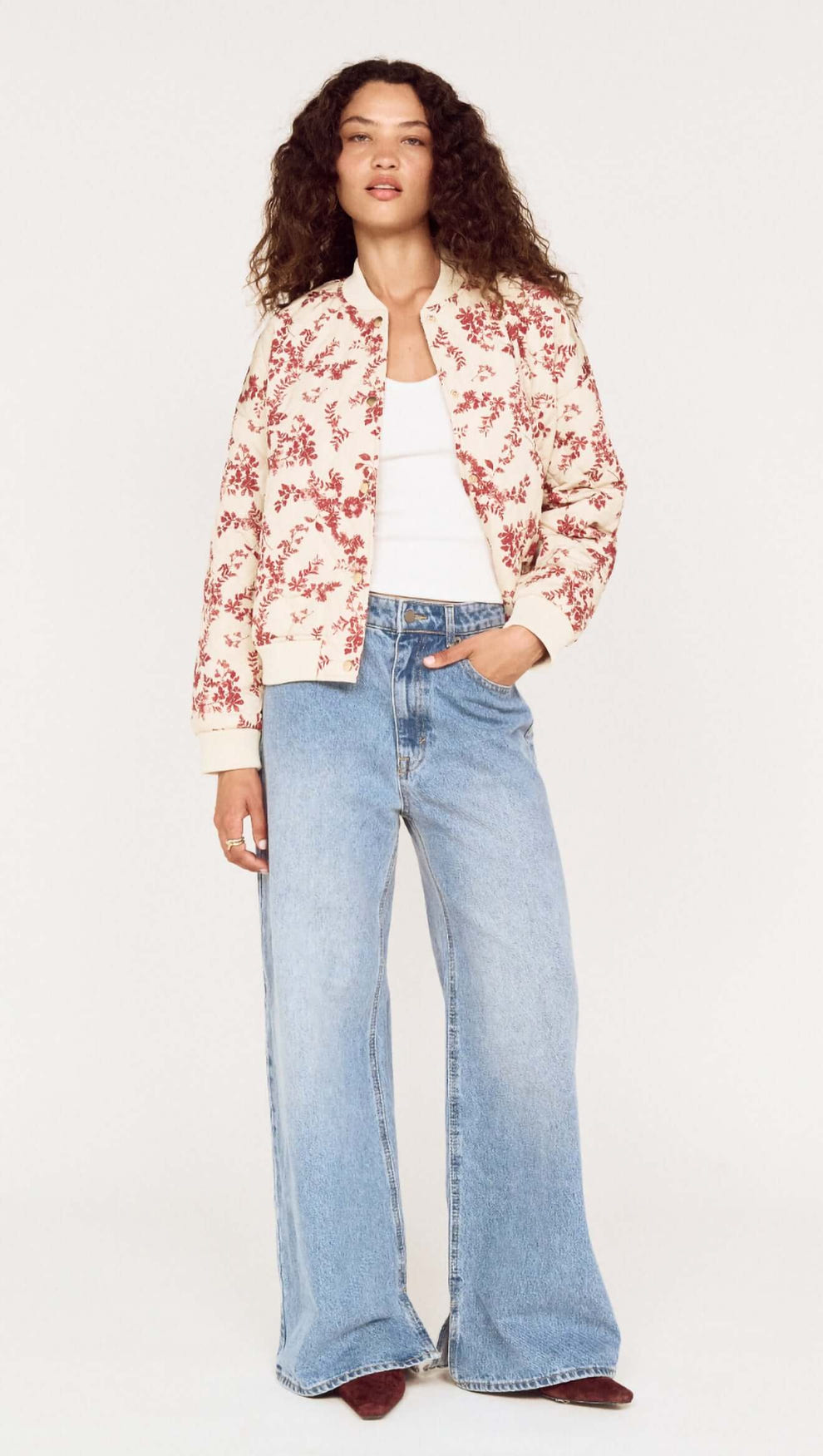 A woman wearing an Autumn Floral Quilted Puffer Jacket with wide-leg jeans, showcasing a stylish autumn look.