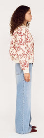 Side view of a model wearing an Autumn Floral Quilted Puffer Jacket with light blue jeans.