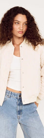 Quilted Bomber Jacket in Warm White worn by model with curly hair, featuring snap button closures and ribbed trims.