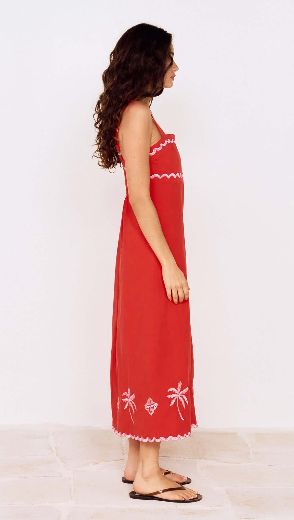 Side view of a model wearing a Red and Pink Embroidery Detail Midi Dress with palm embroidery and adjustable straps.