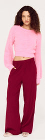 Model wearing the Clio Cropped Fuchsia Pink Fluffy Jumper with wide-leg pants, showcasing a stylish and cozy outfit.