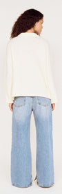 Back view of a model wearing a Gold Detail Relaxed Polo Knit with wide-leg jeans.