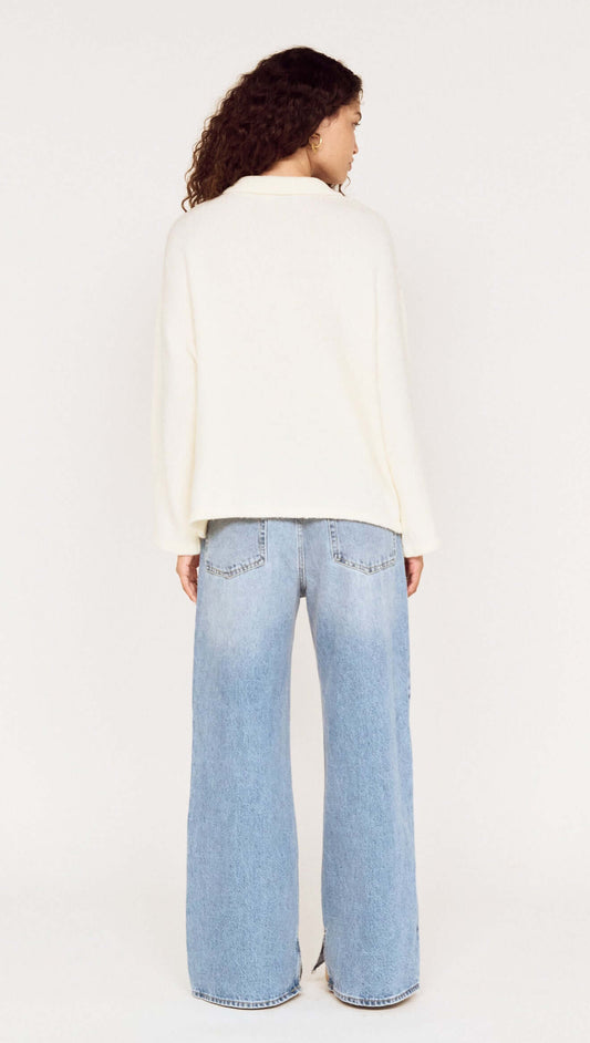 Back view of a model wearing a Gold Detail Relaxed Polo Knit with wide-leg jeans.