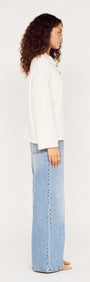 Model showcasing the Gold Detail Relaxed Polo Knit from the side, highlighting its relaxed fit and soft knit fabrication.