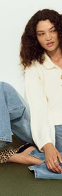 Model wearing Gold Detail Relaxed Polo Knit with buttons, styled with wide-leg jeans and leopard print flats.