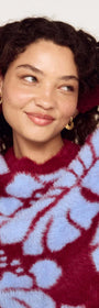 Model wearing an Intarsia Floral Soft Touch Jumper with a playful floral design in red and blue.