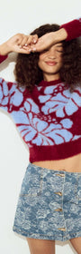 Model wearing an Intarsia Floral Soft Touch Jumper with a floral design, styled with a denim mini skirt.