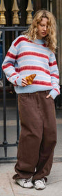Peppermint Stripe Fluffy Jumper worn by a model outside, featuring bold red and blush stripes on a soft blue background.