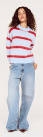 Model wearing a Peppermint Stripe Fluffy Jumper with red and blush stripes over a soft blue base, paired with denim.