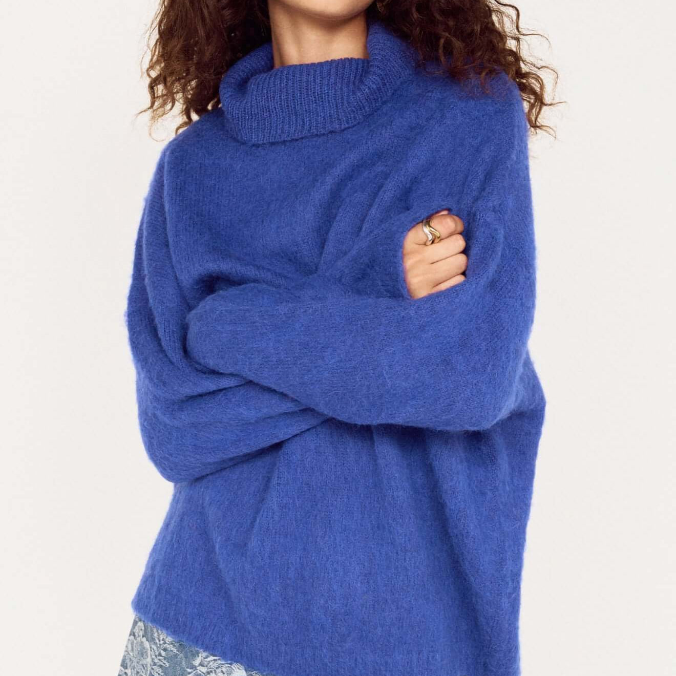 Model wearing a Blue Oversized Roll Neck Jumper, styled casually with a denim mini skirt.