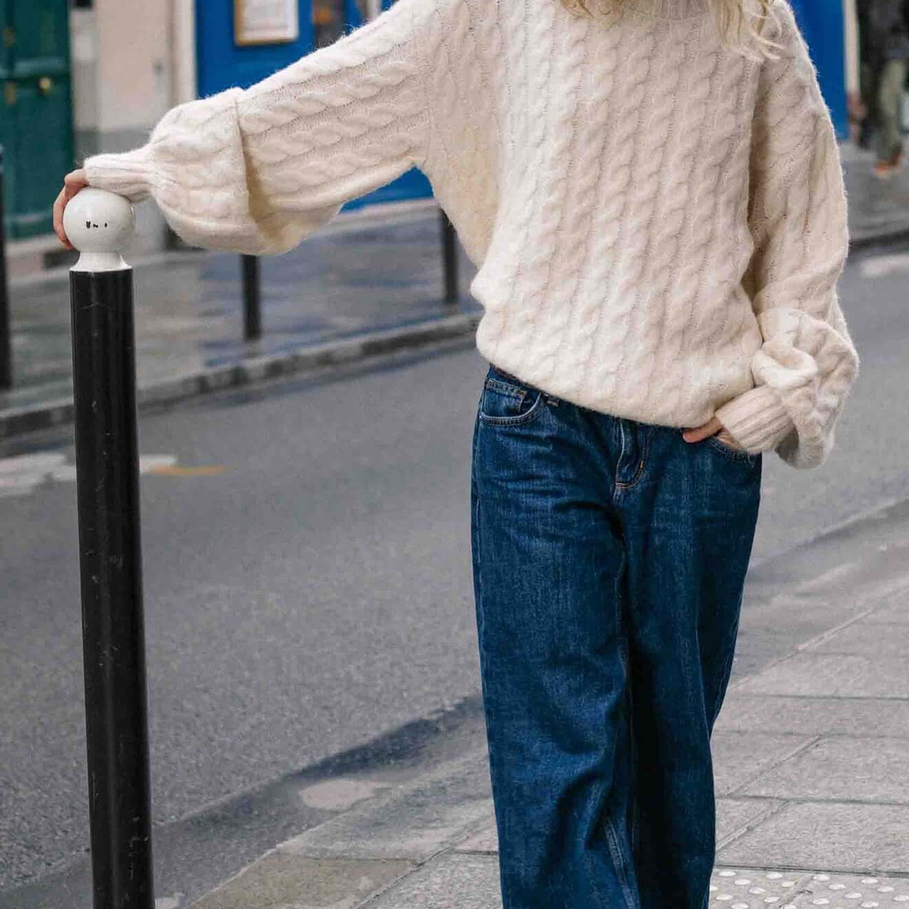 Cream Relaxed Fit Cable Knit Jumper styled with wide-leg jeans in a city street setting.
