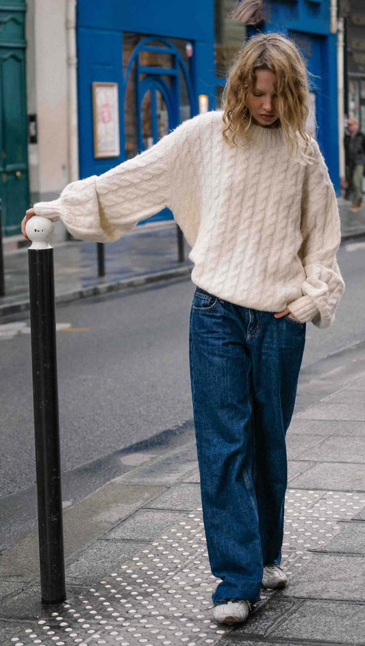 Cream Relaxed Fit Cable Knit Jumper styled with wide-leg jeans in a city street setting.