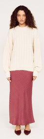 Model wearing a beige knit sweater with a Burgundy Pinstripe Bias Midi Skirt and brown shoes.