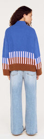 Back view of a woman wearing a cobalt blue intarsia detail jumper with brown and light purple stripes.