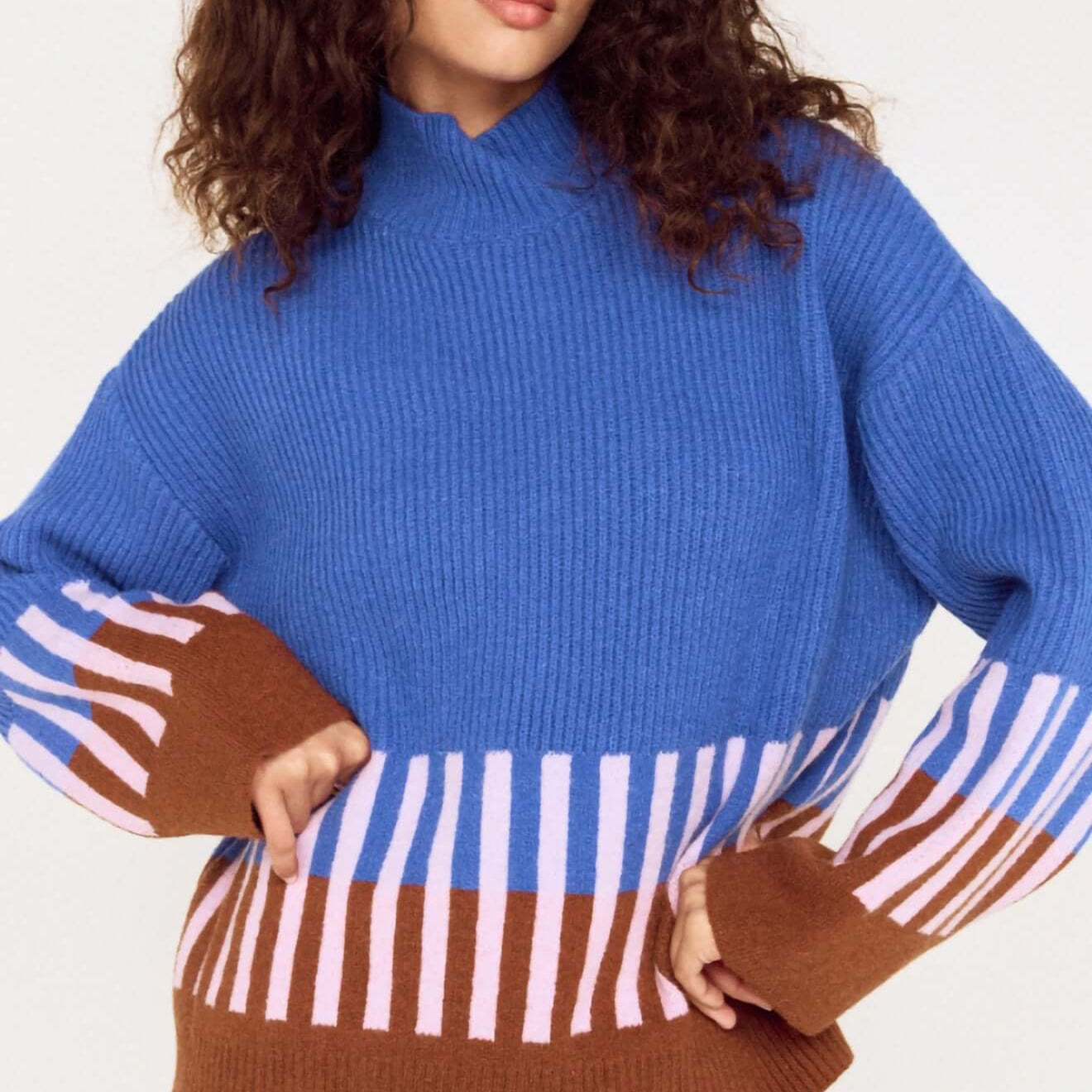 Model wearing a cobalt blue intarsia detail jumper with playful patterns in brown and pink.