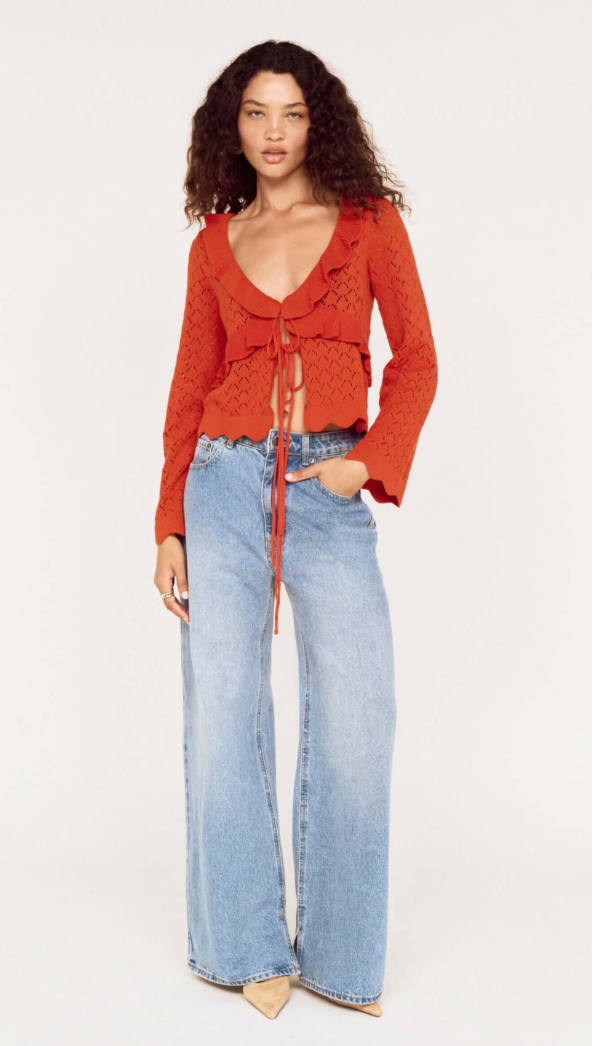 Model wearing a burnt orange pointelle tie front top paired with light blue wide-leg jeans.