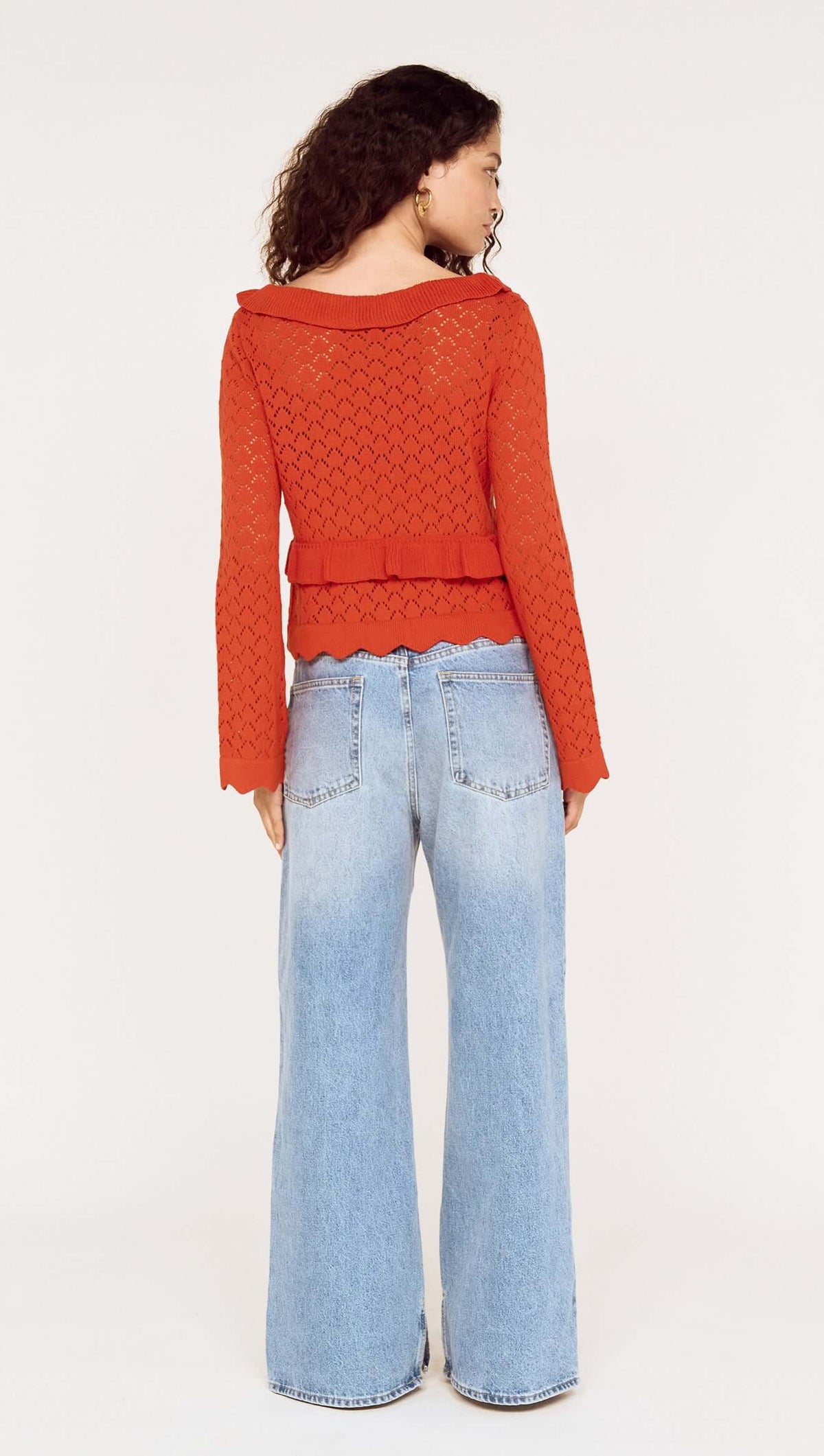 Model wearing a Burnt Orange Pointelle Tie Front Top with flared jeans, showcasing a stylish back view.