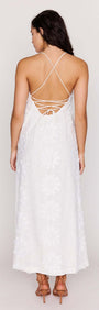 Back view of a woman wearing a White Cotton Floral Applique Lace-Back Maxi Dress showcasing the intricate lace-up detail.