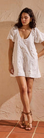 Model wearing a White Cotton Floral Applique Smock Mini Dress with puff sleeves and floral details.