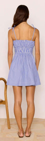 Back view of a woman wearing a Blue & White Stripe Mini Dress with tie straps and shirred bust.