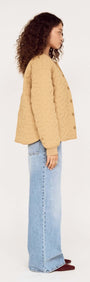 Model wearing a side view of a Beige Floral Quilted Puffer Jacket with light blue jeans.