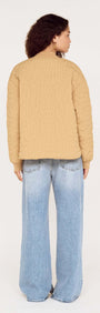 Back view of a model wearing a Beige Floral Quilted Puffer Jacket paired with wide-leg jeans.