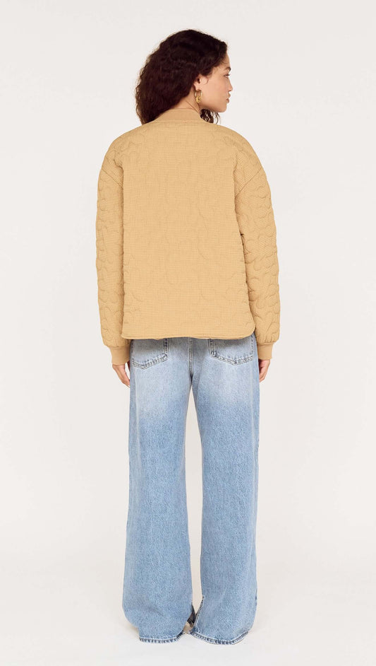 Back view of a model wearing a Beige Floral Quilted Puffer Jacket paired with wide-leg jeans.