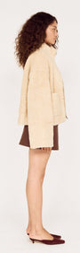 Woman wearing a Beige Teddy Jacket with High Collar, styled with a brown mini skirt and slip-on shoes.