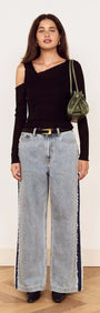 Model showcasing the Black Asymmetric Layered Mesh Top paired with wide-leg jeans and a green handbag.