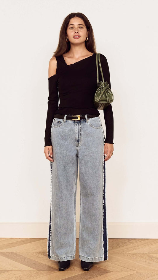 Model showcasing the Black Asymmetric Layered Mesh Top paired with wide-leg jeans and a green handbag.