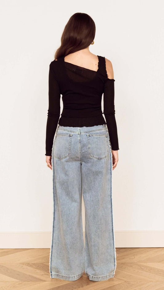 Back view of model wearing Black Asymmetric Layered Mesh Top paired with wide-leg jeans.