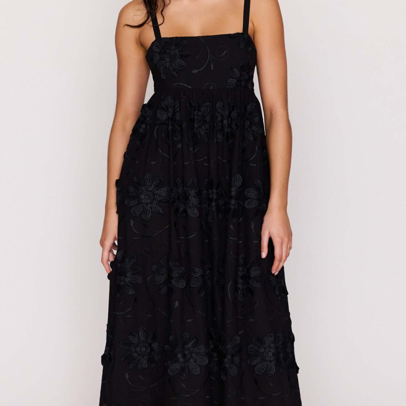 Black Tiered Cotton Applique Midi Dress worn by a model, showcasing elegant floral detailing and a flowing silhouette.