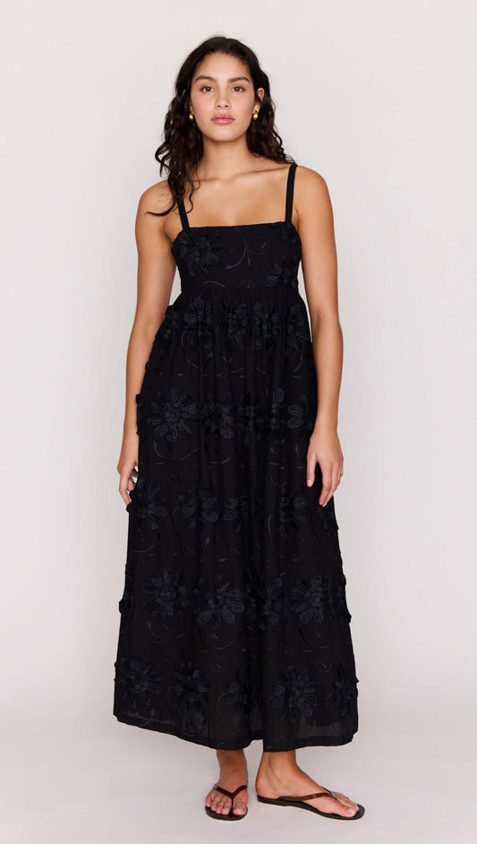 Black Tiered Cotton Applique Midi Dress worn by a model, showcasing elegant floral detailing and a flowing silhouette.
