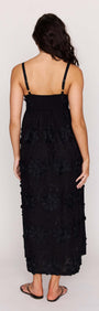 Back view of a woman wearing a Black Tiered Cotton Applique Midi Dress with floral detailing.