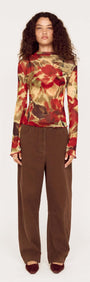Model wearing brown mid rise barrel leg jeans with floral long-sleeve top, showcasing a modern fashion look.