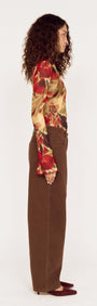 Model showcasing Brown Mid Rise Barrel Leg Jeans from the side, paired with a colorful floral top.